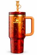 A Stanley tumbler with a red and orange floral pattern, a solid orange handle, and a gold lid featuring a pineapple pour spout, shown on a white background.